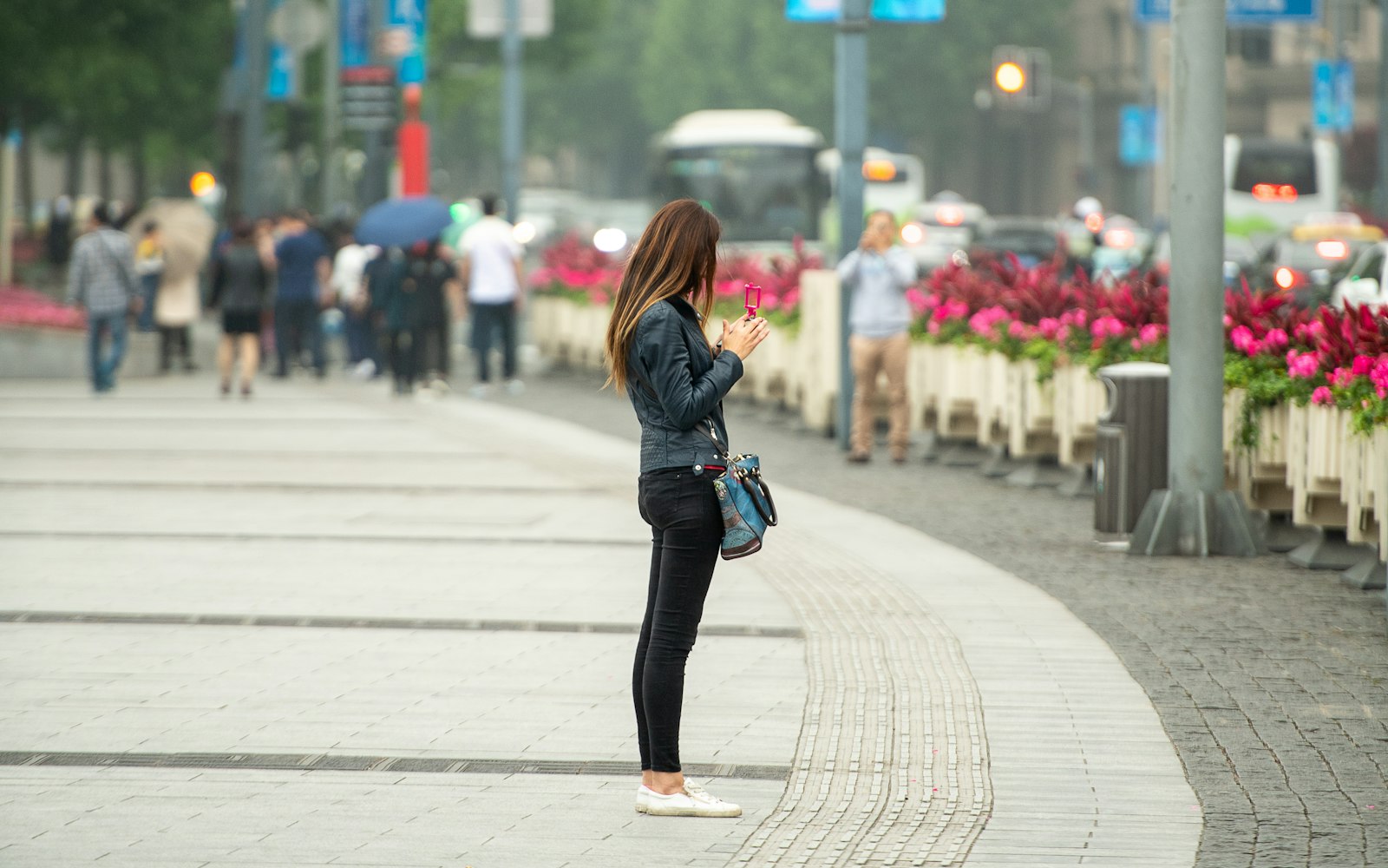 Pedestrian pausing on a downtown sidewalk to look something up on her phone