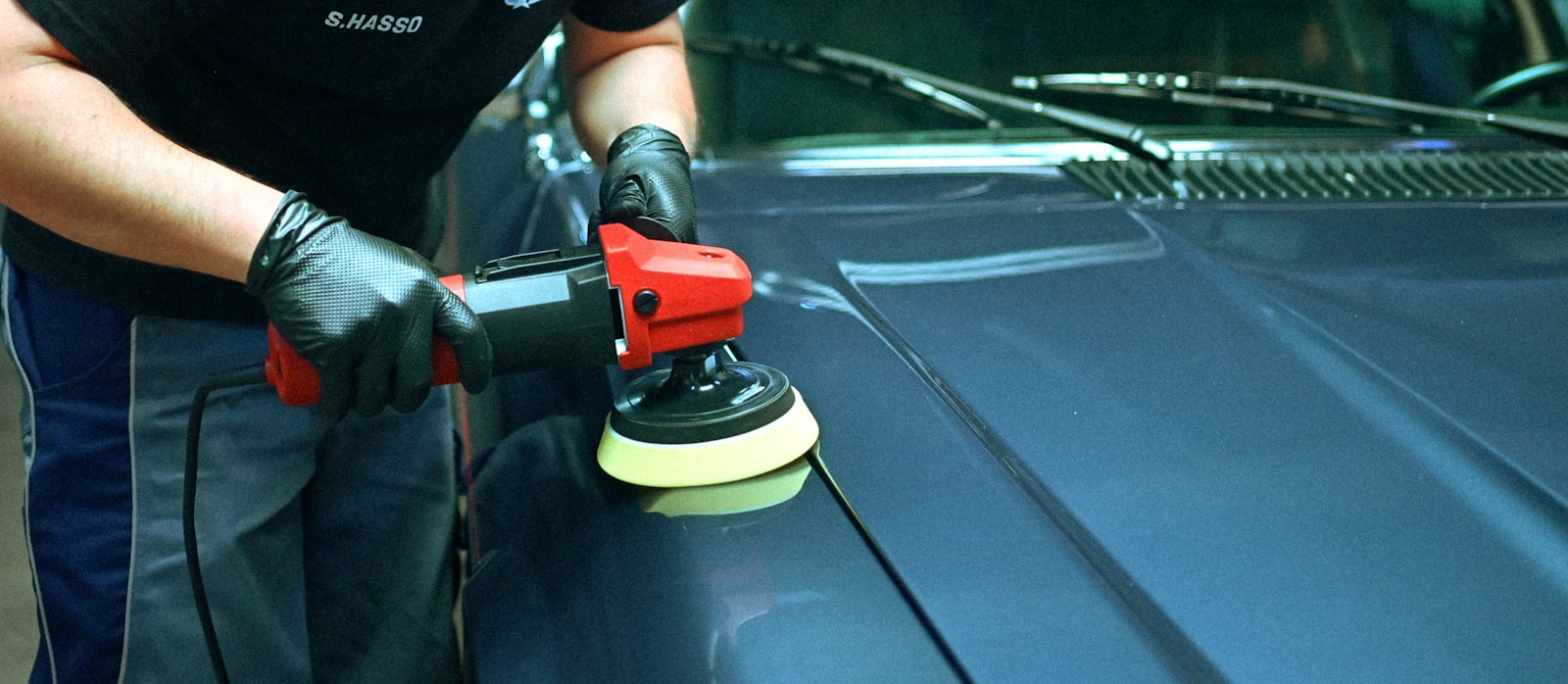 Auto detailer polishing the paintwork of a car inside a professional detailing studio