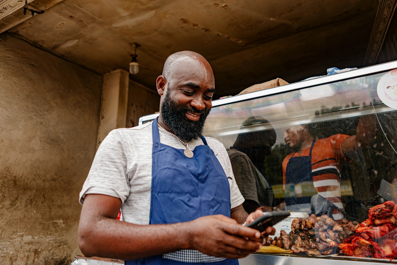 Small business owner in an apron checking his Google Business Profile listing on a phone