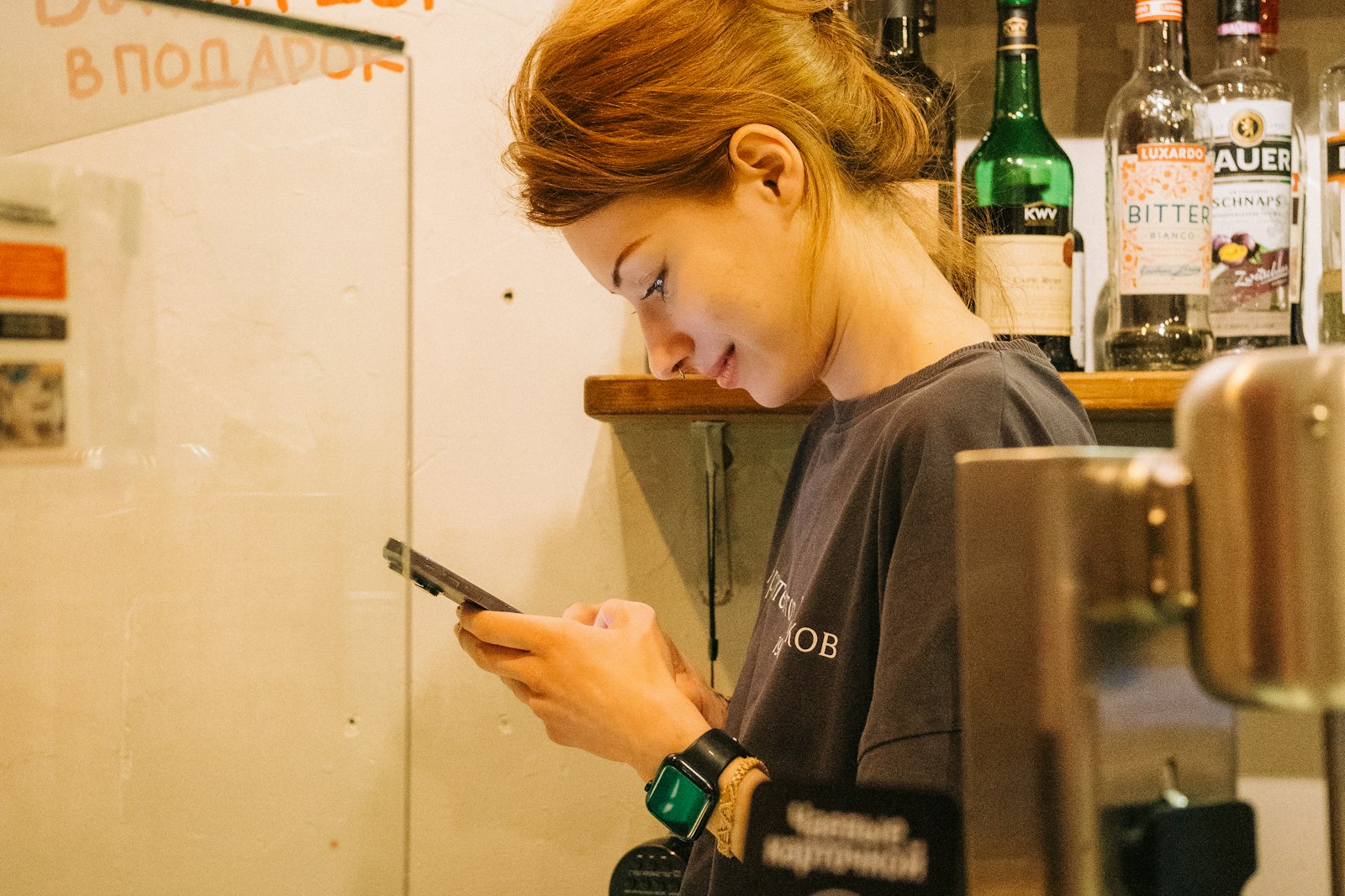 Small business owner checking her phone behind the counter of a cafe bar