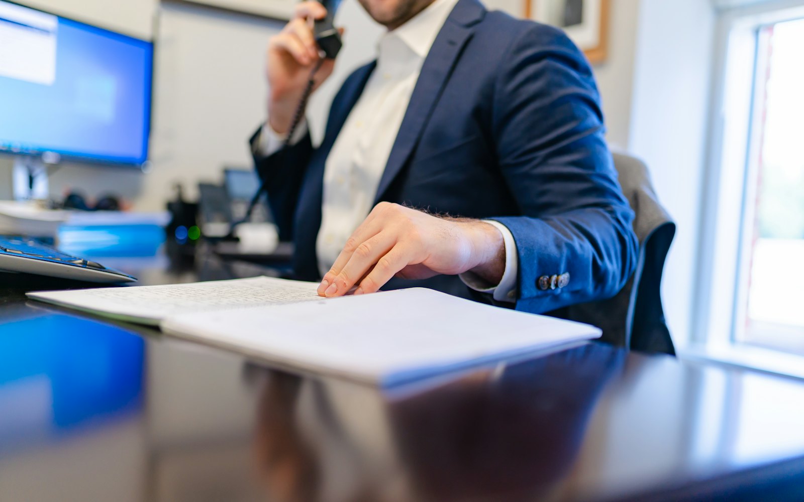 Lawyer at a desk taking a phone call while reading through a printed document