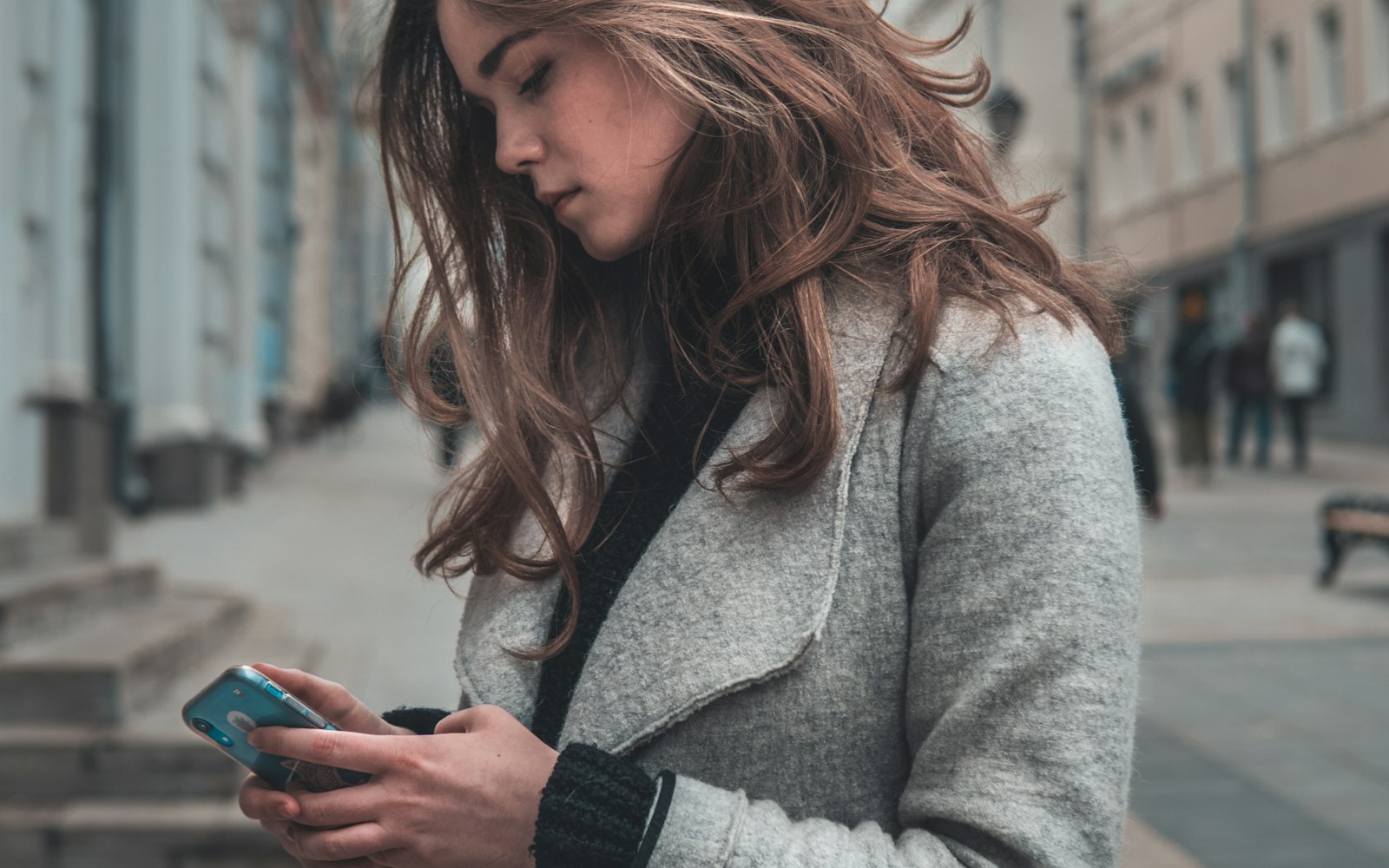Woman on a city sidewalk searching her phone for a nearby local business on Google