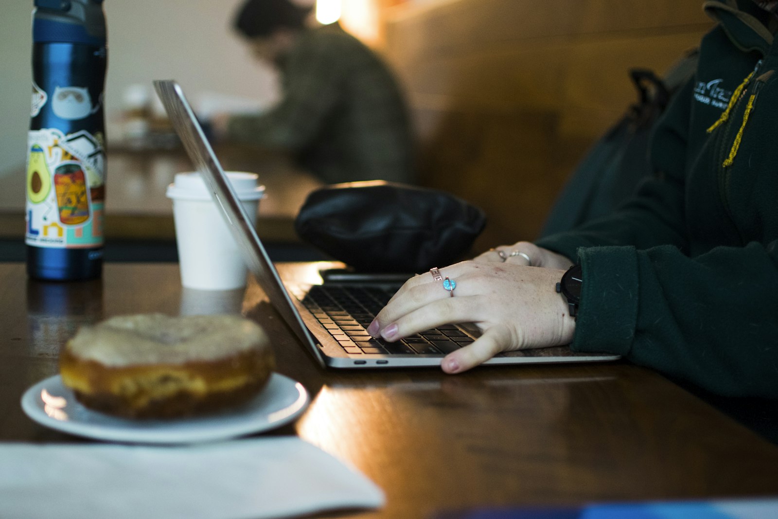 Business owner writing a reply to a customer review on a laptop at a wooden table