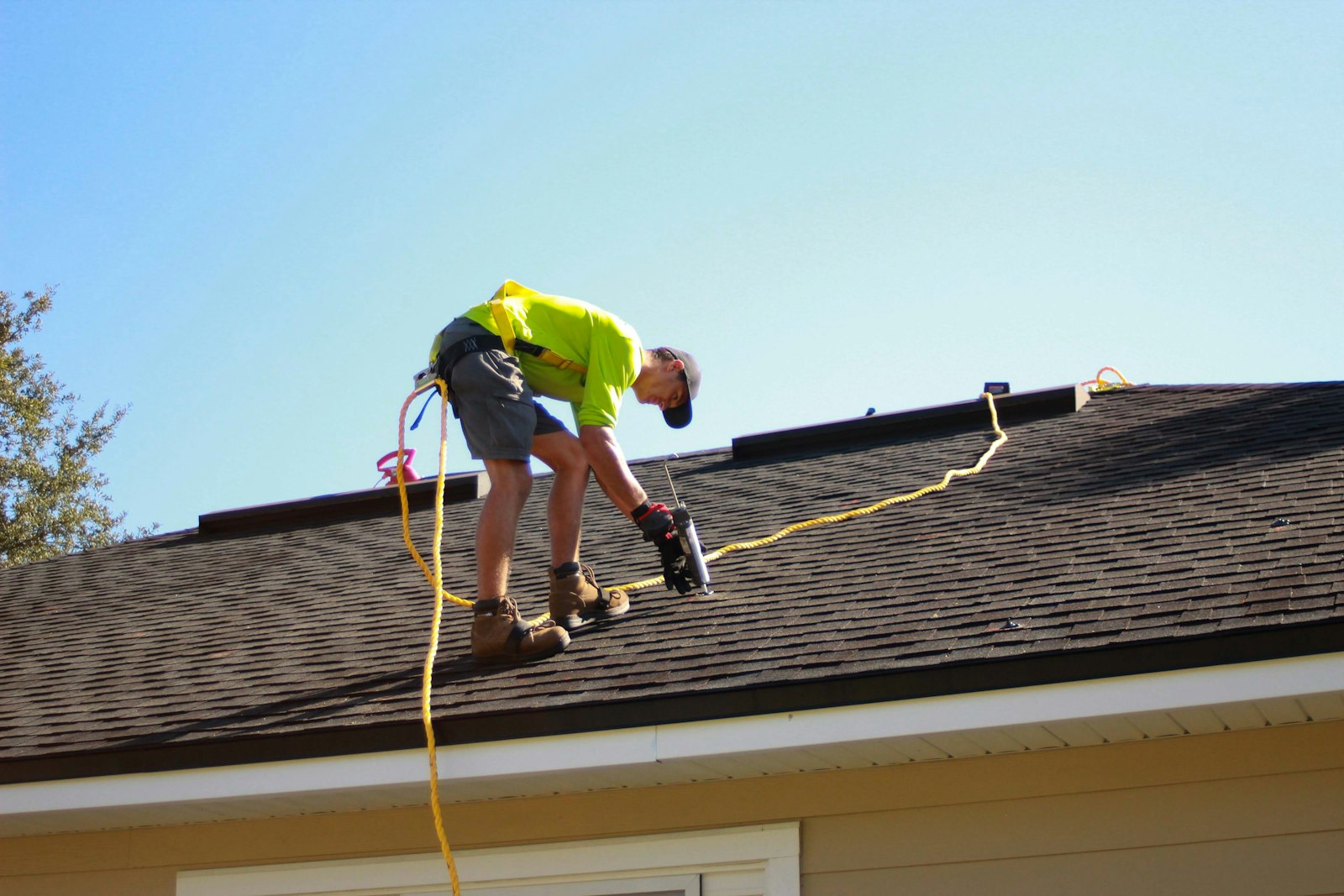 Roofing contractor on a residential roof installing shingles on a clear day