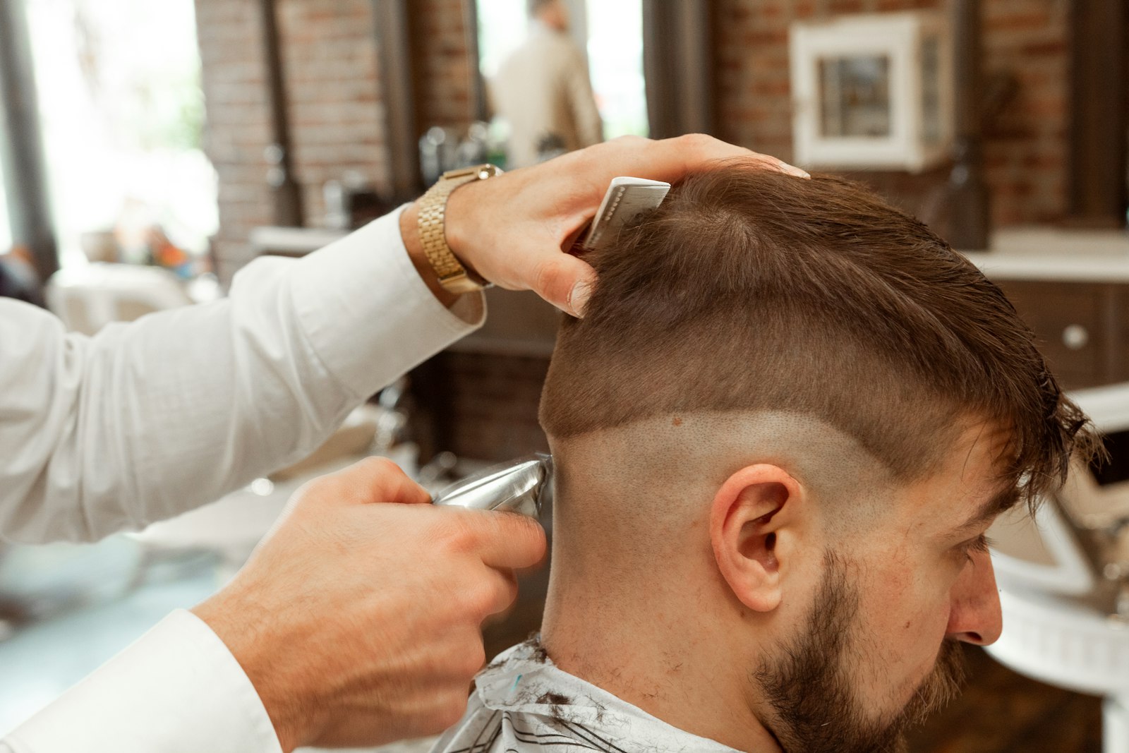 Barber cutting a client's hair in a modern barbershop with styling chairs
