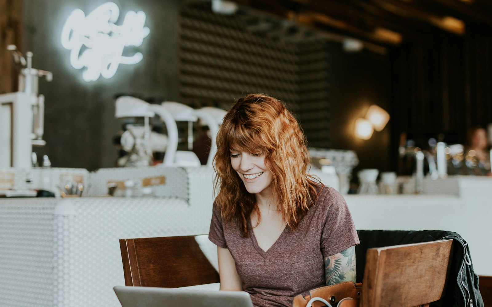 Small business owner smiling while comparing website pricing options on her laptop in a Toronto café