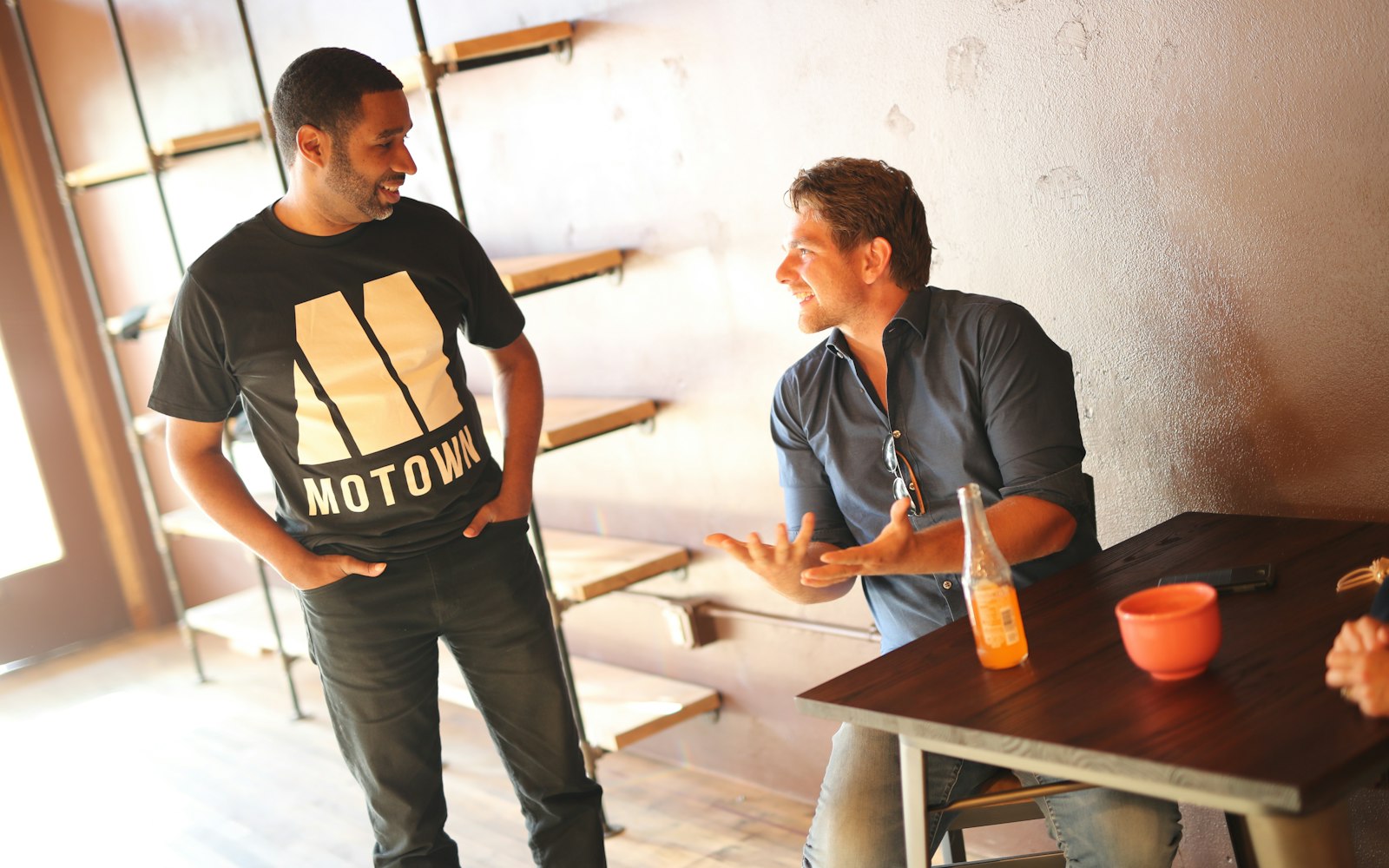 Two men in conversation, one recommending a business to the other
